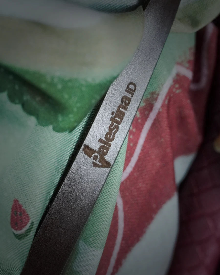 A Palestina.id lanyard strap crossing the watermelon-printed hijab